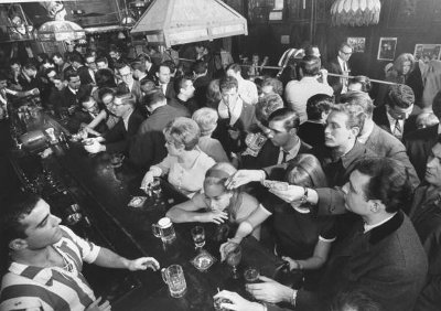 A busy bar with people enjoying their drinks.