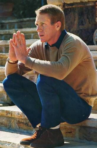 Steve mcqueen sitting on stone stairs.